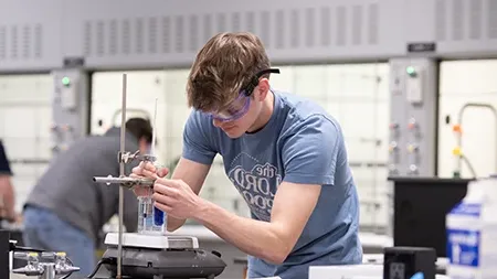 Male student working with equipment in a science laboratory.