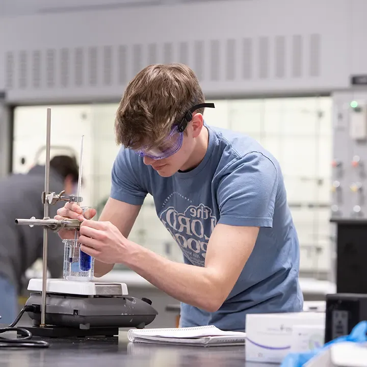 Male student working with equipment in a science laboratory.